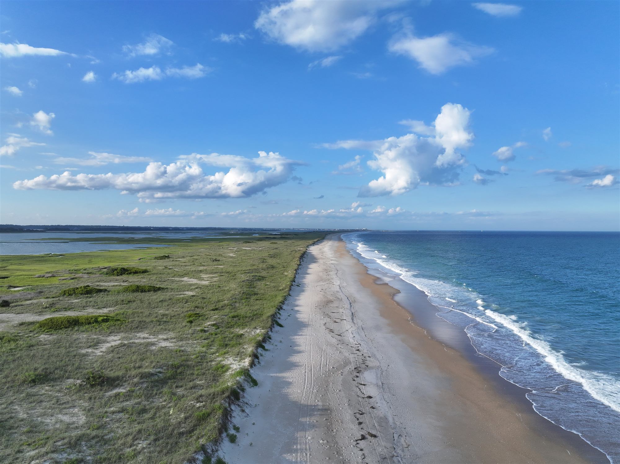 Aerial view of Masonboro Island's beach and marsh under big summer clouds