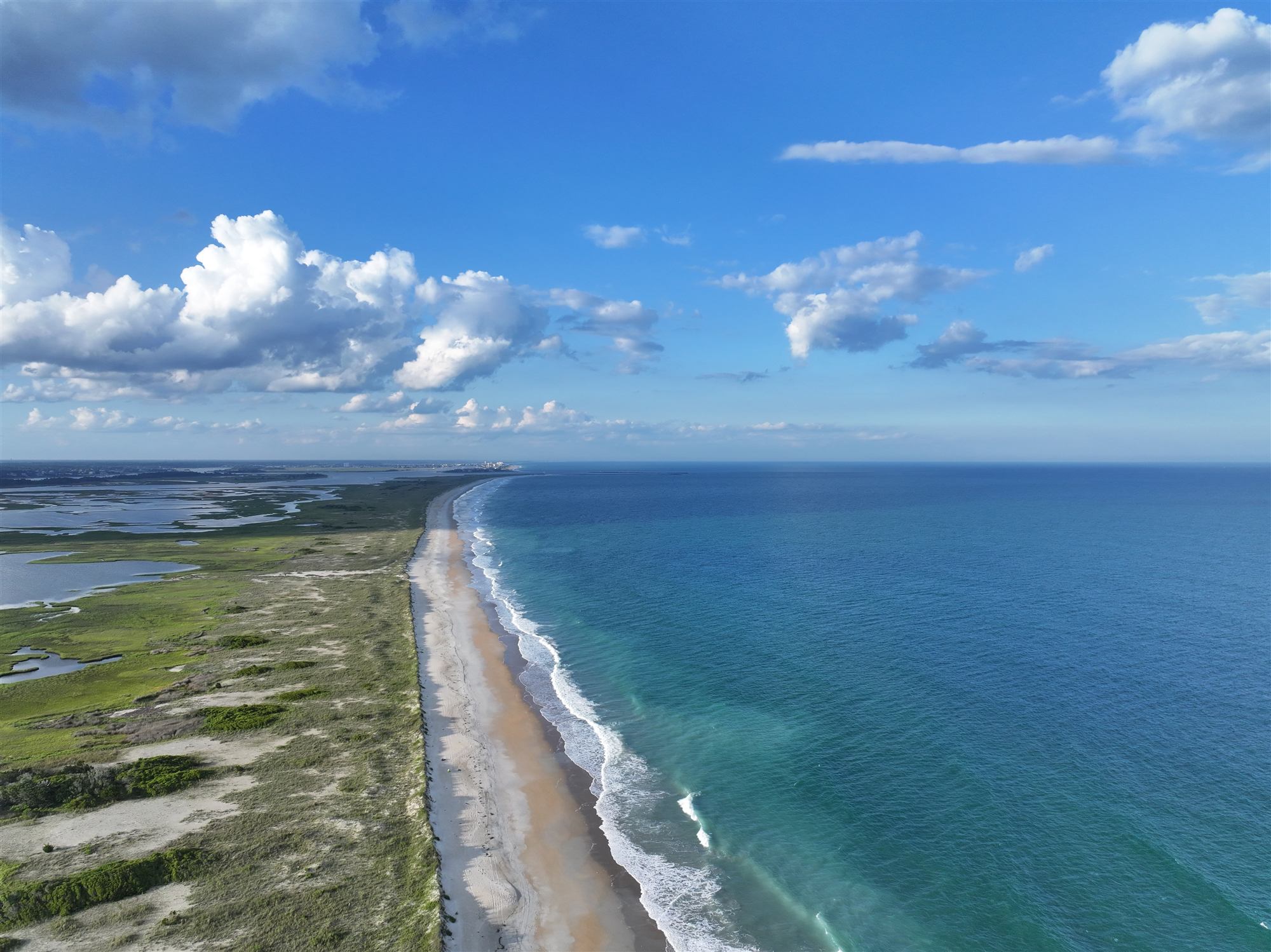 Aerial view down the length of Masonboro Island: ocean beach on one side, dunes and salt marsh on the other