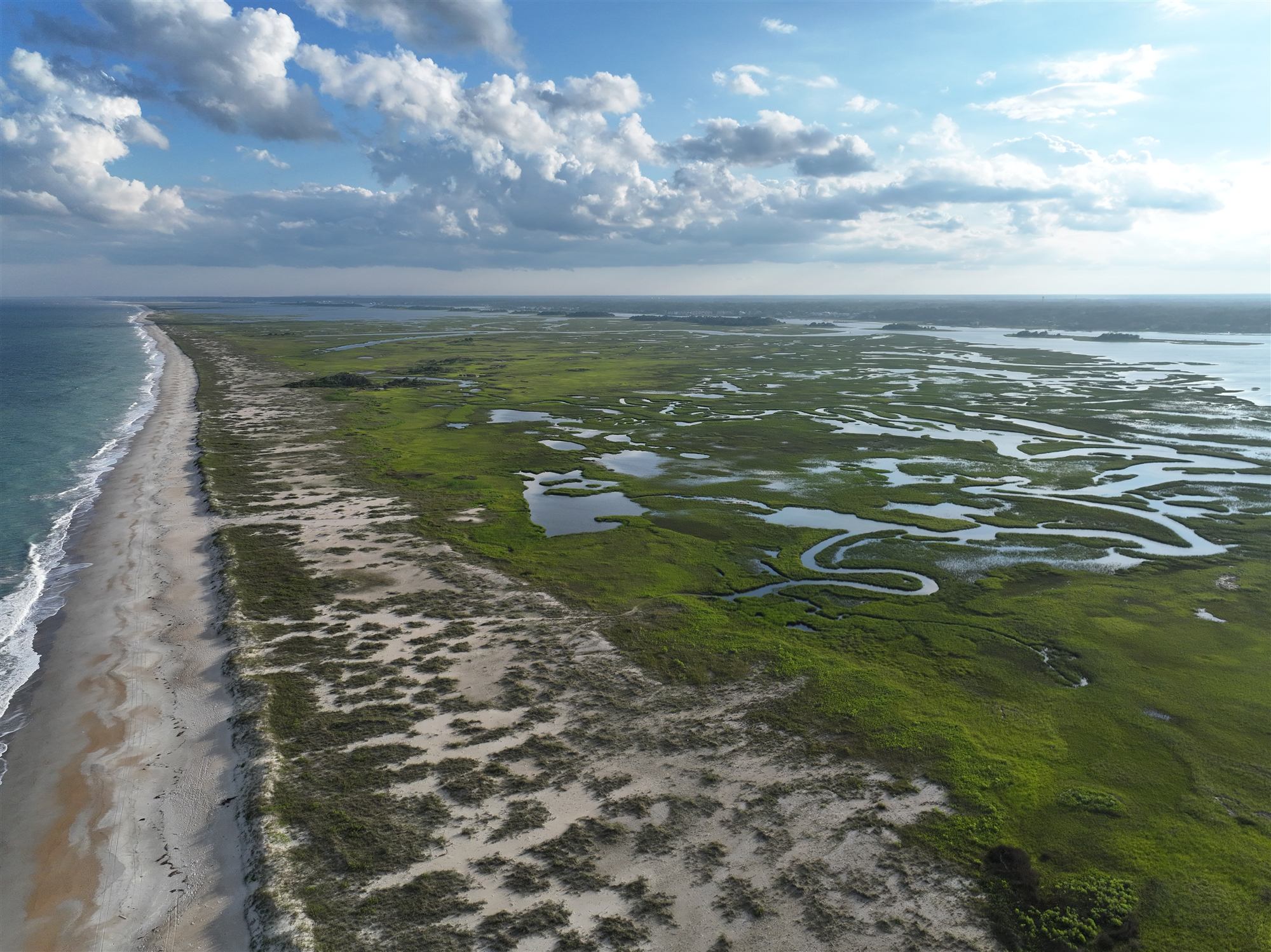 Aerial view of Masonboro's habitats: ocean beach, dunes, and salt marsh threaded with tidal creeks