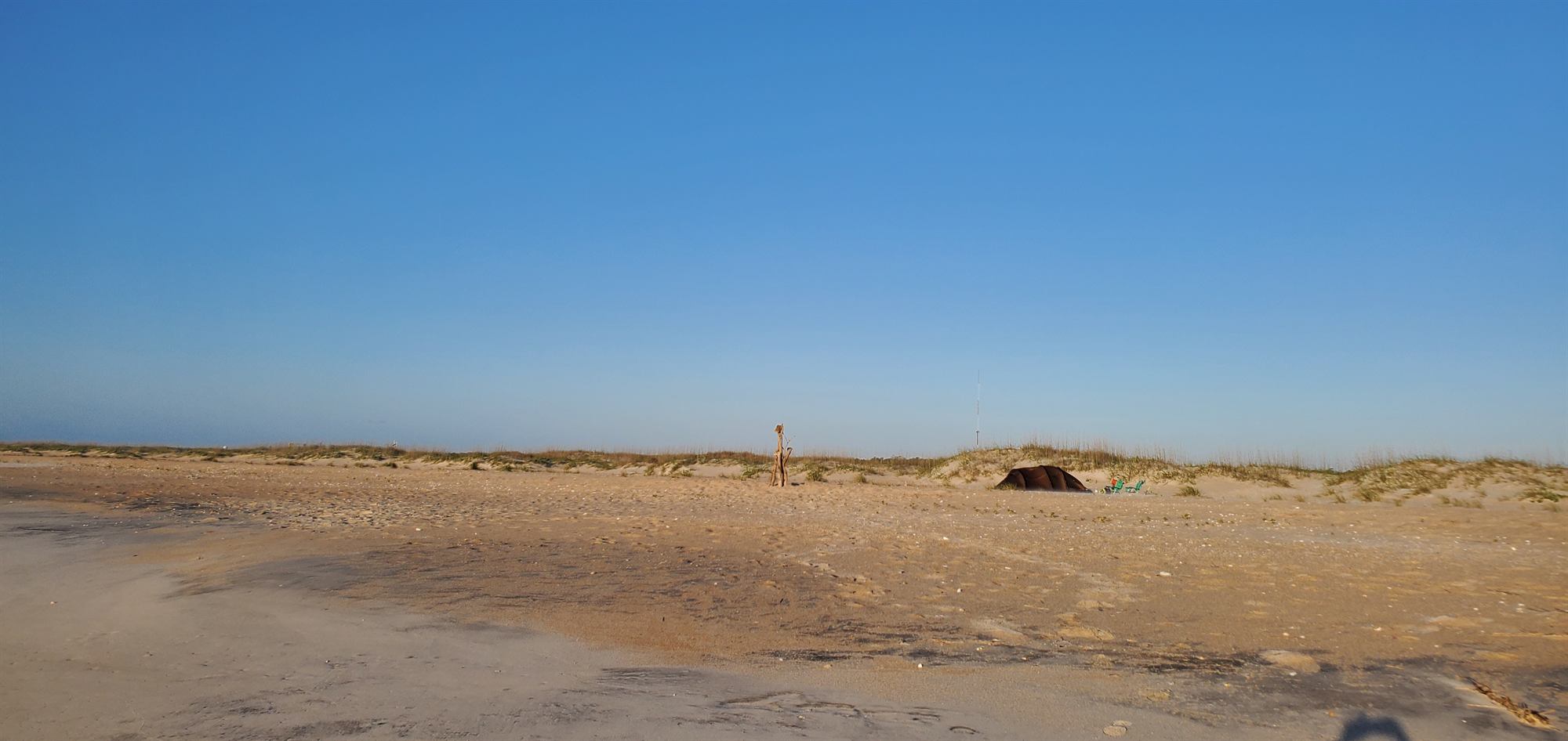 A single tent on a wide, empty stretch of Masonboro Island beach below the dunes